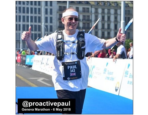 ProactivePaul in full running kit, smiling and thumbs up, as he crosses the finish line of the Geneva Marathon 2018